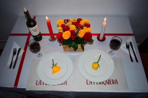 a table with two plates and a vase of flowers and candles at Hotel Campestre La Periquera in Villa de Leyva