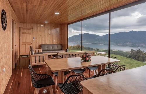 a room with tables and chairs and a large window at Refugio del Neusa in Cogua