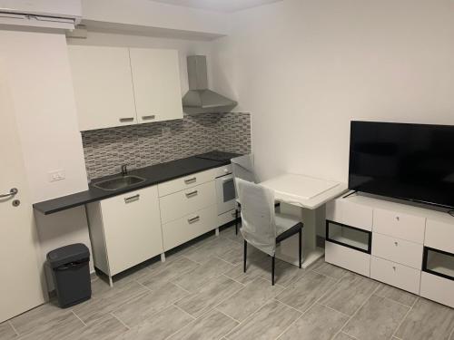 a kitchen with white cabinets and a table and a television at Apartments Old Town Izola in Izola