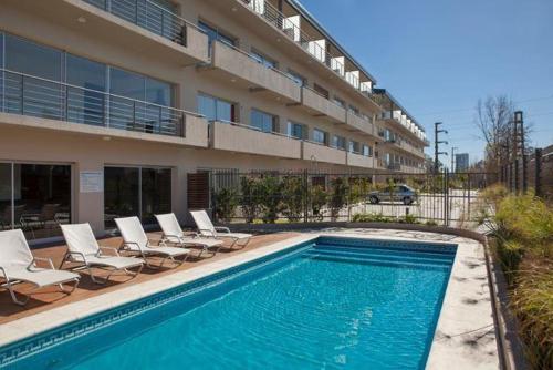 a swimming pool with chairs and a building at Departamentos Farley in Tigre