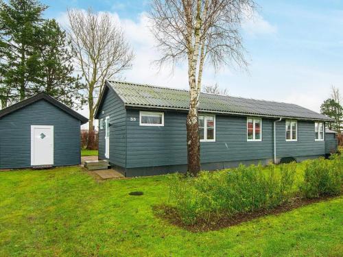 a blue house with a tree in a yard at 8 person holiday home in Haderslev in Haderslev