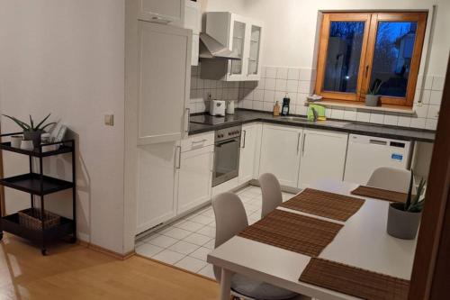 a kitchen with white cabinets and a table with chairs at Helle Terrassenwohnung am Waldrand in Nürtingen