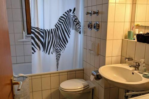 a bathroom with a zebra shower curtain and a sink at Helle Terrassenwohnung am Waldrand in Nürtingen