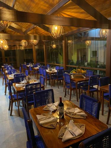 a dining room with wooden tables and blue chairs at The Madalena Pousada in Imbassai