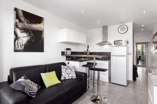 a living room with a black couch and a kitchen at Village Naturiste - Le Caresse Port Nature Luxe in Cap d'Agde