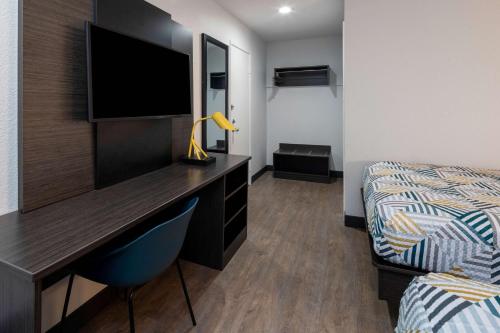 a bedroom with a desk with a television and a bed at Motel 6-Fontana, CA in Fontana