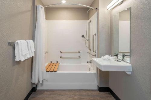 a bathroom with a white tub and a sink at Motel 6-Fontana, CA in Fontana
