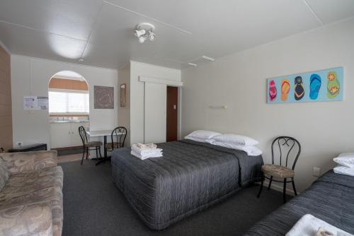a bedroom with a bed, chair, desk and a television at Sierra Beachfront Motel in Kaikoura