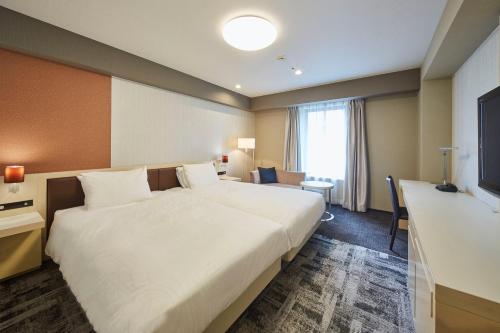 a hotel room with a large bed and a desk at Richmond Hotel Narita in Narita