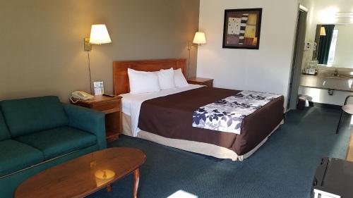 a hotel room with a bed and a green couch at Travelers Inn & Suites in Sumter