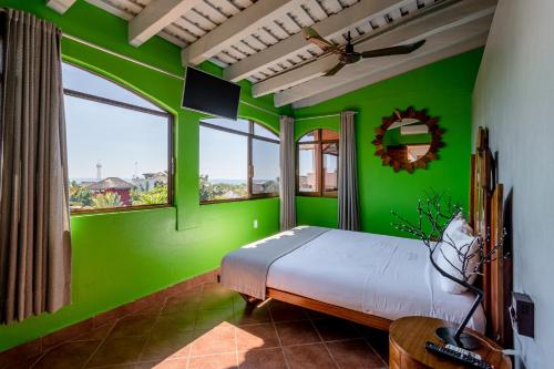 a bedroom with green walls and a bed in a room at Suites La Hacienda in Puerto Escondido