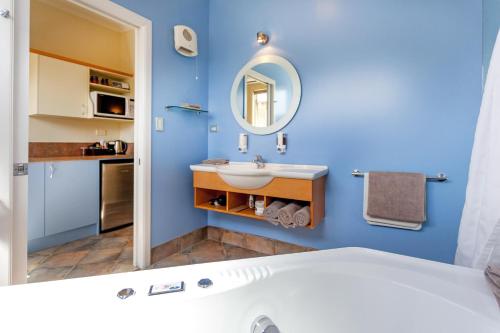 uma casa de banho azul com um lavatório e um espelho em Tuscany On Thames em Thames