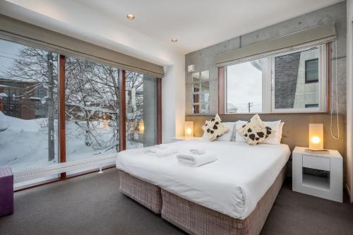 Un dormitorio con una cama grande y una ventana grande. en Kitanishi 2 by H2 Life, en Kutchan