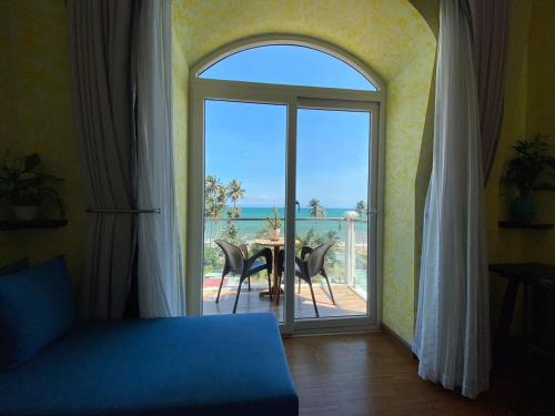 a room with a large window with a table and a view of the ocean at La Marina Boutique Hotel & Spa in Mui Ne