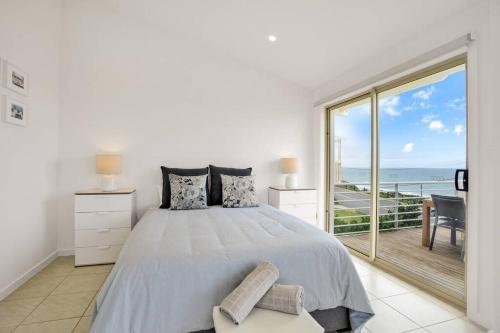 a white bedroom with a bed and a balcony at THE LIDO BEACH FRONT in Port Elliot