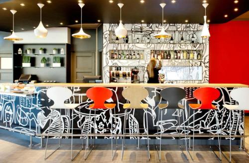 a bar with colorful chairs and a wall withcriptions at Ibis Warszawa Ostrobramska in Warsaw