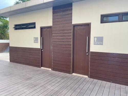 duas portas castanhas na lateral de um edifício em Khentdrick's Place at Holland Park Southwoods em Biñan