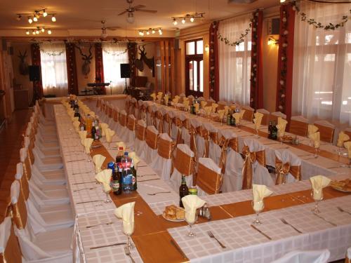 a long table in a room with white tables and chairs at Árnyas Thermal Camping és Üdülőpark in Püspökladány