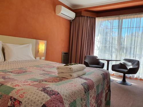 ein Hotelzimmer mit einem Bett, einem Stuhl und einem Fenster in der Unterkunft Motel Margeurita in Queanbeyan