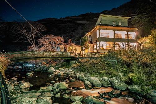 a house on a bridge over a river at 自家源泉かけ流しの温泉宿 櫻井邸 in Shimo-sagano