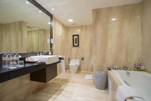 La salle de bains est pourvue d'une baignoire, d'un lavabo et de toilettes. dans l'établissement Eastparc Hotel Yogyakarta, à Yogyakarta