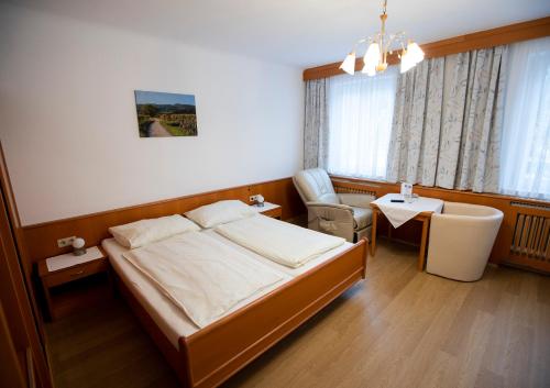 een slaapkamer met een bed, een stoel en een tafel bij Hotel-Gasthof Martinek in Baden