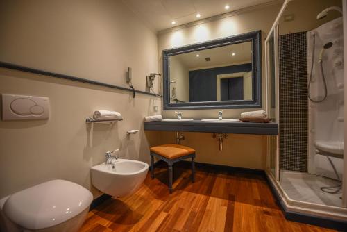 bagno con lavandino, servizi igienici e specchio di The Tuscanian Hotel a Lucca