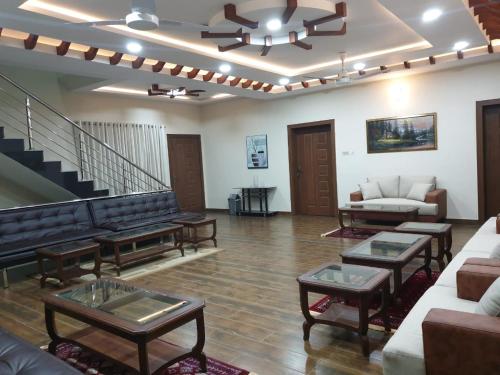 a living room with couches and tables and a staircase at Alpha Guest House in Rawalpindi