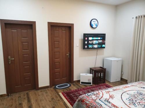 a bedroom with two doors and a tv on the wall at Alpha Guest House in Rawalpindi