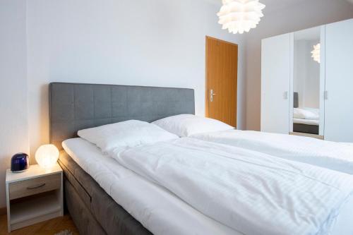 a bedroom with a large white bed with a gray headboard at Mittelweg 6 Wohnung 3 in Grömitz
