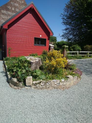 a red building with a garden in front of it at La Nouvelle Criqueboise in Criquebeuf-en-Caux