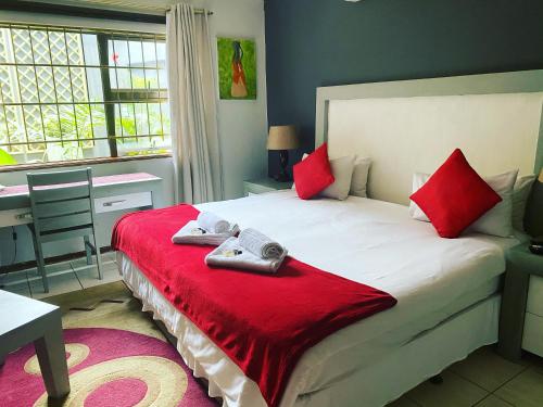 a bedroom with a large bed with red pillows at Marion Lodge in Johannesburg