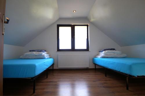 a attic room with blue beds and a window at Komfortowe domki nad jeziorem - Zielony domek 1 in Kruklanki