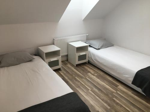 Habitación con 2 camas, paredes blancas y suelo de madera. en apartament en Rzeszów