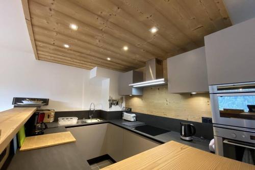 une cuisine avec des appareils blancs et un plafond en bois dans l'établissement Les 360 - Apt 12 - BO Immobilier - Châtel - Châtel Multipass Été 2025 en option au tarif de 3euros par jour et par personne, à Châtel