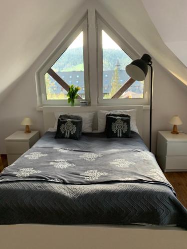 a bedroom with a bed with two windows at Apart Orkana 10D Zakopane in Zakopane