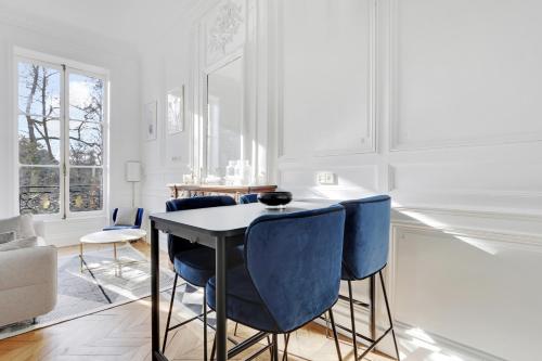 a white kitchen with blue chairs and a table at Maison Labruyère Bordeaux - Jardin Public in Bordeaux