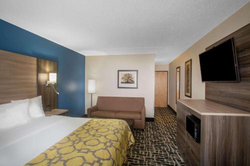 a hotel room with a bed and a couch and a television at Baymont by Wyndham Branson - On the Strip in Branson