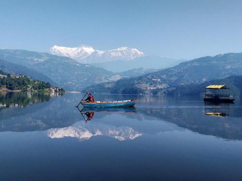 a boat on the water with mountains in the background at Pokhara Youth Hostel in Pokhara