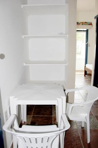 a white table and two white chairs in a room at Pousada Terceiro Espaço in Guaibim