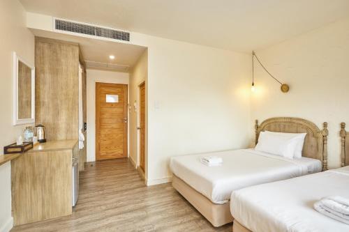 a hotel room with two beds and a bathroom at Talay Hotel and Villa Cha-am in Cha Am