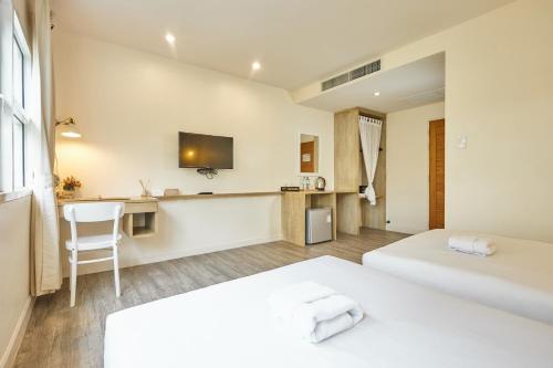 a hotel room with two beds and a desk at Talay Hotel and Villa Cha-am in Cha Am