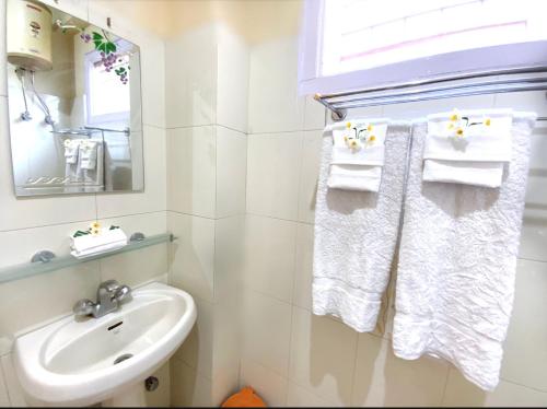 a white bathroom with a sink and towels at Hotel Sanjeevny in Bajaura