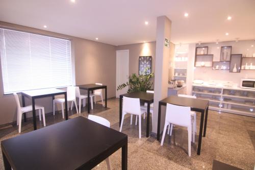 a dining room with tables and white chairs at Hotel Alpha in Uberlândia
