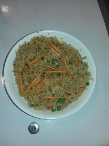 a white plate of rice with carrots and peas at Hotel The Shivaay - Delight Inn Rishikesh in Rishīkesh