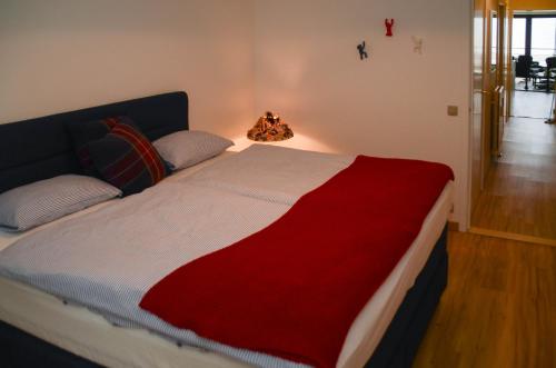 a bedroom with a bed with a red and white blanket at appartement DE WATERLIJN in Knokke-Heist