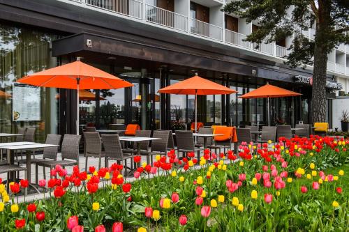 a garden of flowers with tables and umbrellas in front of a building at Original Sokos Hotel Tapiola Garden Espoo in Espoo