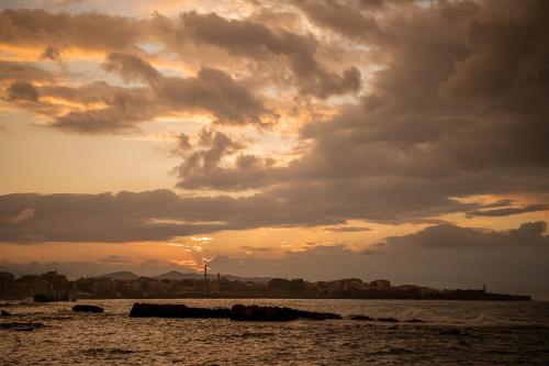 a sunset over a body of water with clouds at The Tanneries Hotel & Spa - a Member of Design Hotels in Chania Town