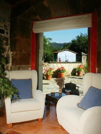 a living room with two white chairs and a window at Hotel Rural Sucuevas in Mestas de Con