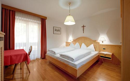 a bedroom with a bed and a table and a window at Garni Rives in Ortisei